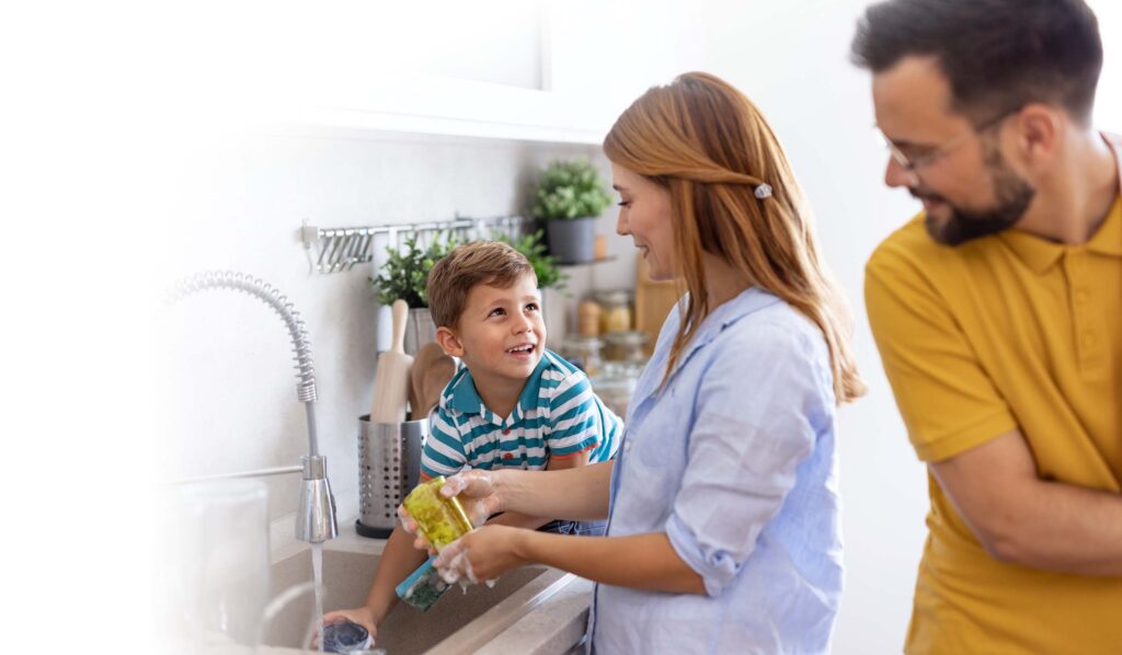 Family washing dishes together in modern kitchen space